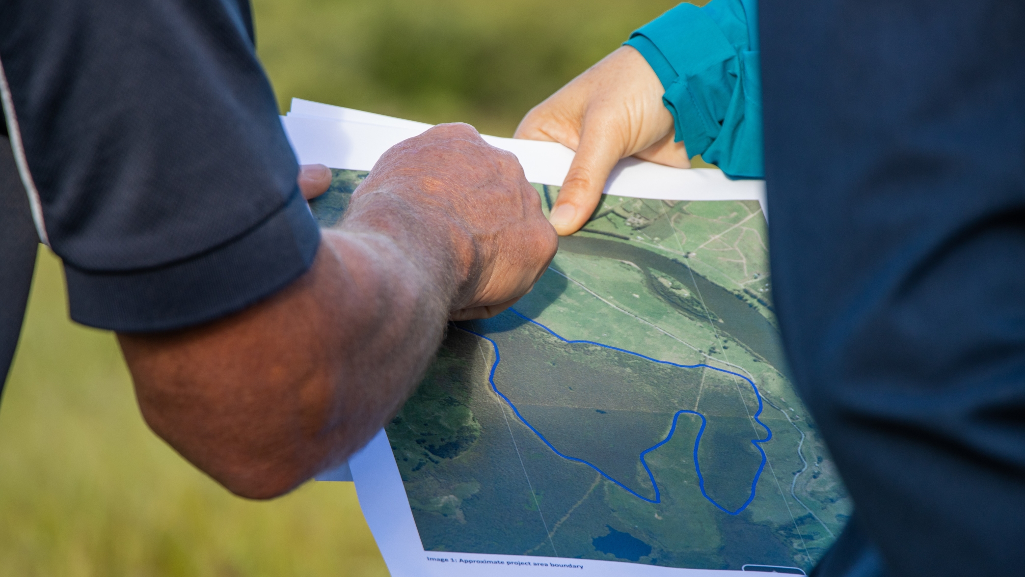Close up view of two people discussing points on a printed aerial map of some land